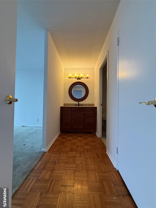 hallway featuring a textured ceiling and parquet flooring