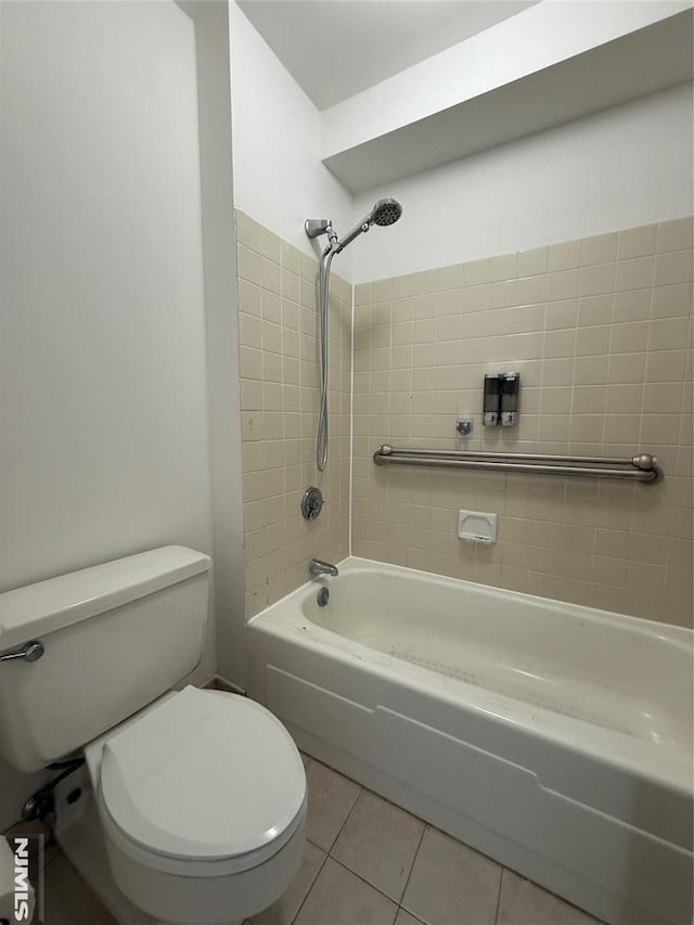 bathroom with tiled shower / bath, tile patterned floors, and toilet