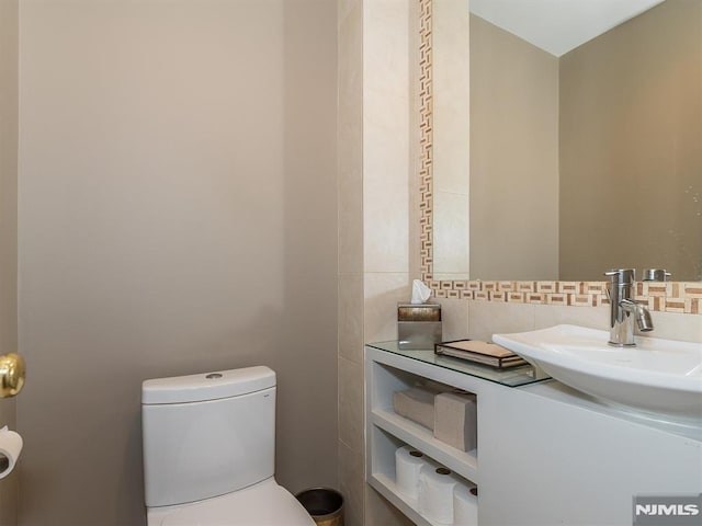 bathroom with toilet, vanity, and backsplash