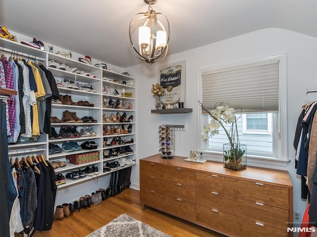 spacious closet featuring light wood-type flooring and an inviting chandelier