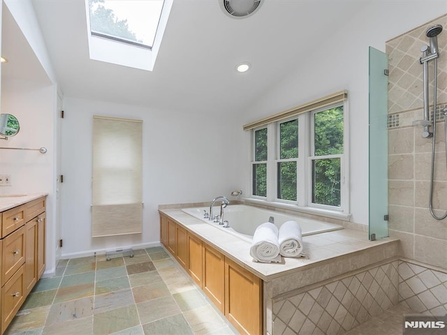 bathroom featuring vanity, vaulted ceiling with skylight, and shower with separate bathtub