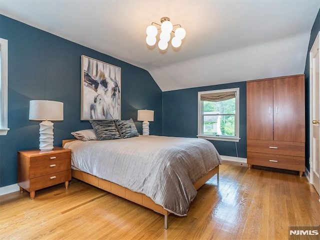 bedroom with light wood-type flooring and lofted ceiling