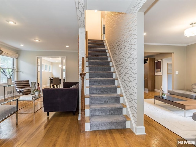 stairs featuring ornamental molding and hardwood / wood-style flooring