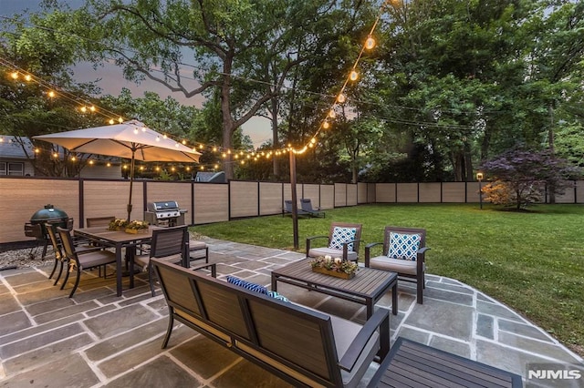 patio terrace at dusk featuring a lawn, an outdoor living space, and area for grilling