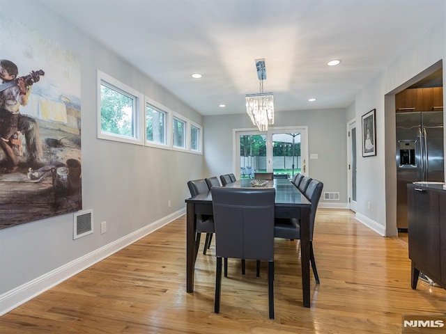 dining space with light hardwood / wood-style flooring and a notable chandelier