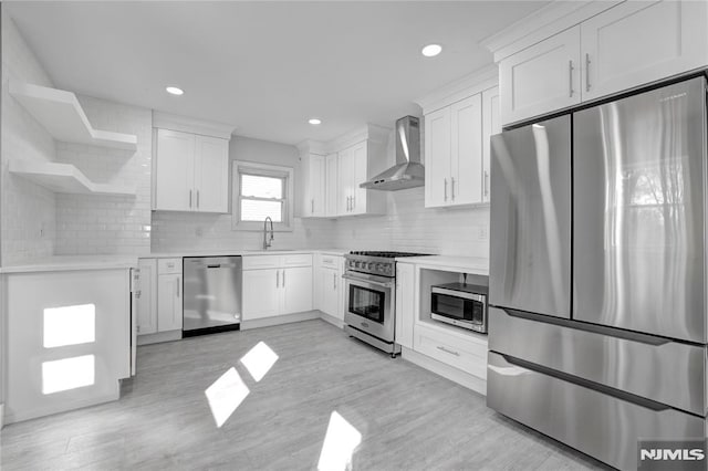 kitchen with white cabinets, wall chimney range hood, and appliances with stainless steel finishes