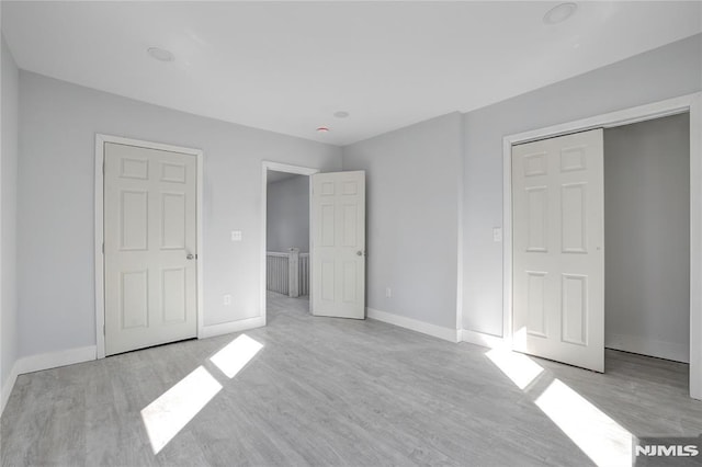 unfurnished bedroom featuring light wood-type flooring and a closet