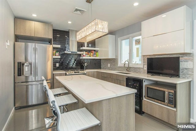 kitchen featuring sink, a breakfast bar area, beverage cooler, a kitchen island, and appliances with stainless steel finishes