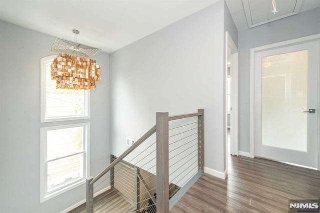 corridor with an inviting chandelier and dark wood-type flooring