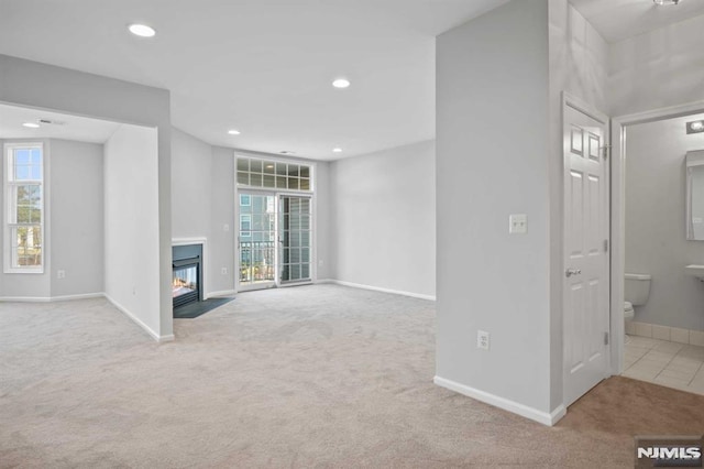 unfurnished living room featuring light carpet and plenty of natural light