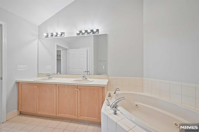 bathroom with vanity, tile patterned flooring, tiled bath, and vaulted ceiling