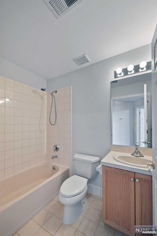 full bathroom with vanity, tile patterned flooring, tiled shower / bath combo, and toilet