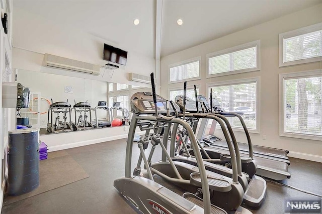 exercise room with a high ceiling and an AC wall unit