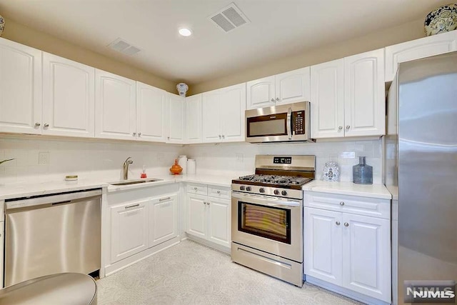 kitchen with stainless steel appliances, white cabinetry, backsplash, and sink