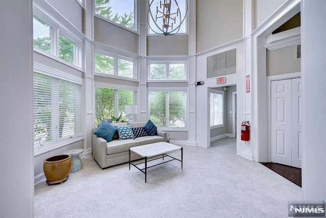 living room with a high ceiling, light colored carpet, and a notable chandelier