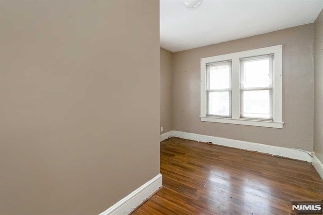 unfurnished room with dark wood-type flooring