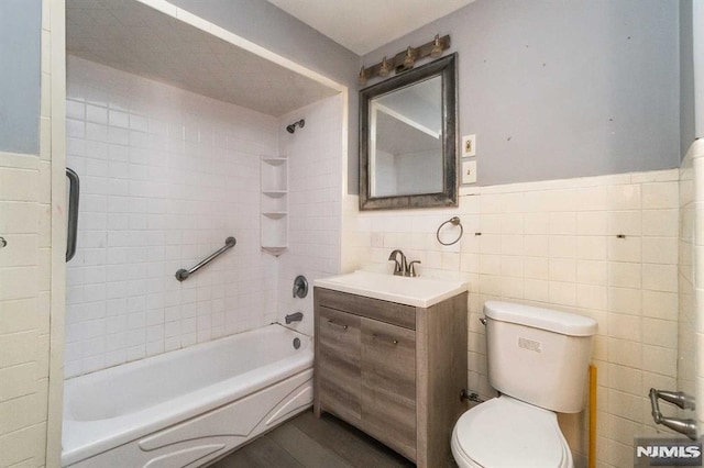 full bathroom with toilet, vanity, tile walls, and tiled shower / bath combo