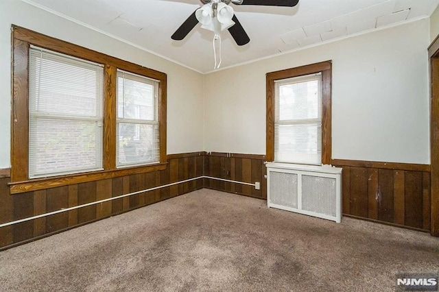 spare room with ornamental molding, ceiling fan, radiator heating unit, and carpet flooring