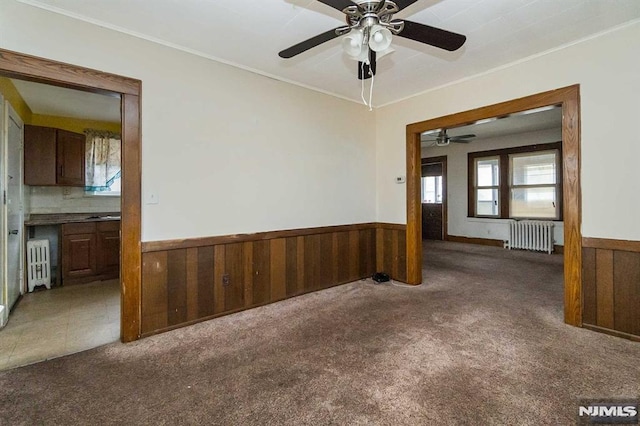 empty room featuring ceiling fan, radiator heating unit, and carpet