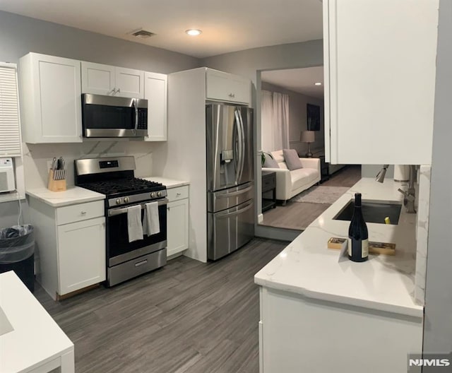 kitchen featuring sink, appliances with stainless steel finishes, dark hardwood / wood-style flooring, and white cabinetry