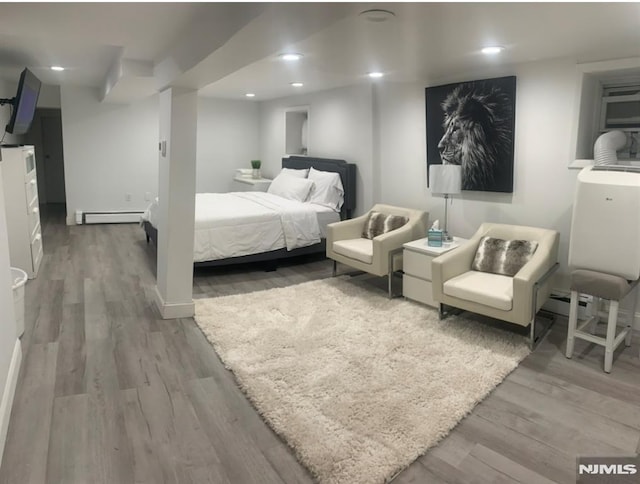 bedroom featuring a baseboard heating unit and hardwood / wood-style floors