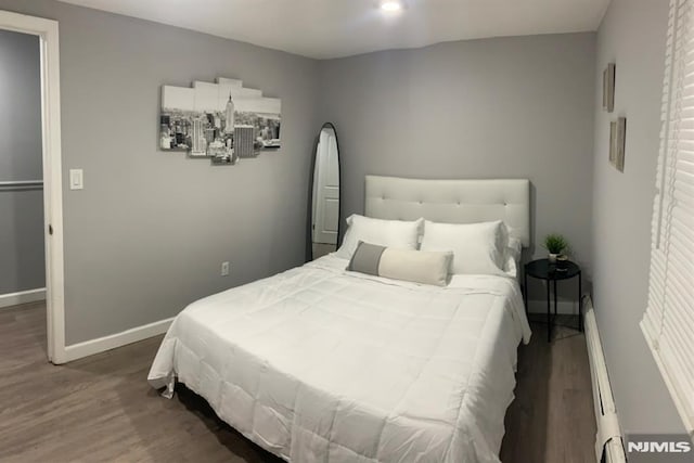 bedroom with baseboard heating and dark hardwood / wood-style floors