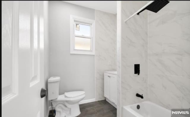 full bathroom featuring vanity, tiled shower / bath combo, and toilet