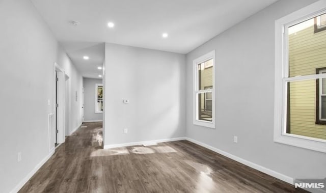 empty room featuring dark wood-type flooring and plenty of natural light