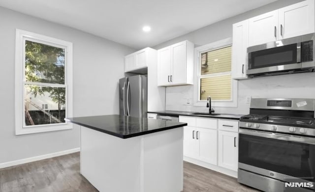 kitchen with sink, white cabinets, dark hardwood / wood-style floors, a kitchen island, and appliances with stainless steel finishes