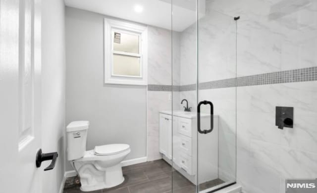 bathroom with a shower with door, vanity, and toilet