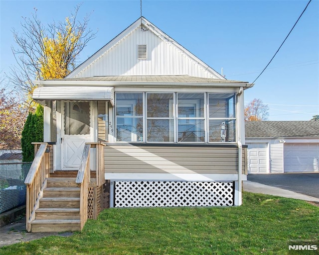 bungalow-style house featuring a sunroom, a garage, and a front yard