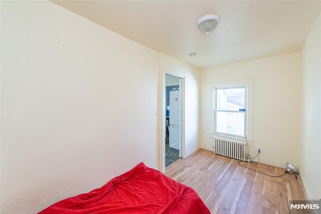 bedroom with light wood-type flooring and radiator heating unit