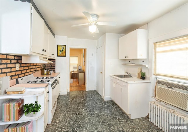 kitchen with white cabinetry, ceiling fan, radiator, white gas range, and sink