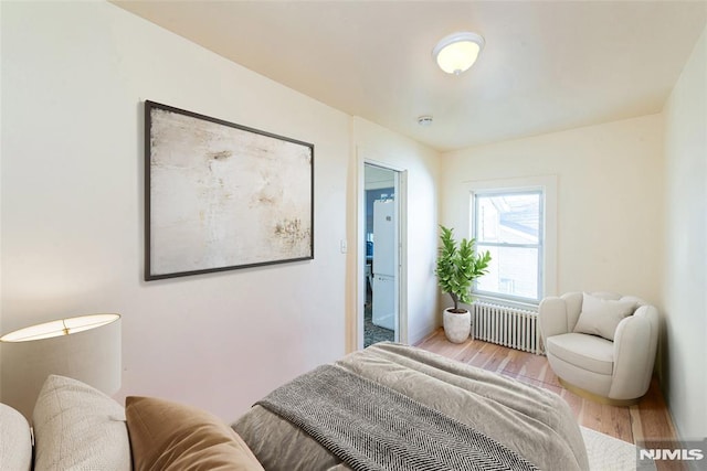 bedroom with light wood-type flooring and radiator heating unit