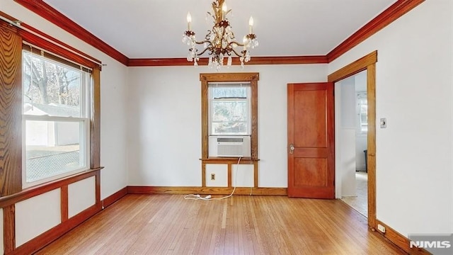 spare room featuring cooling unit, a chandelier, ornamental molding, and light hardwood / wood-style floors