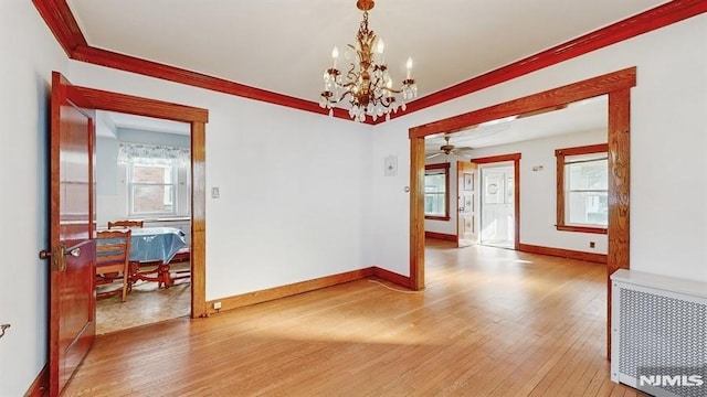 unfurnished room with a healthy amount of sunlight, light hardwood / wood-style flooring, radiator heating unit, and ceiling fan with notable chandelier