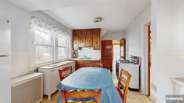 kitchen with sink, white appliances, and radiator heating unit