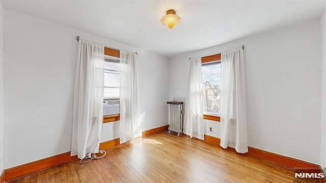 empty room with radiator and hardwood / wood-style flooring