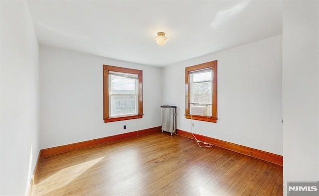 unfurnished room featuring radiator and hardwood / wood-style floors