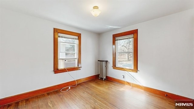 empty room featuring radiator, wood-type flooring, and cooling unit