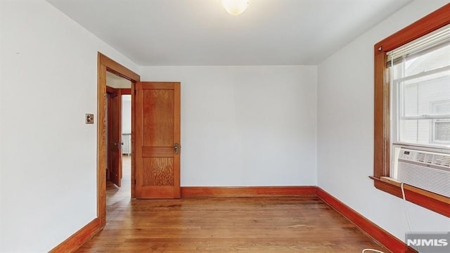 unfurnished room with light hardwood / wood-style floors, cooling unit, and a wealth of natural light