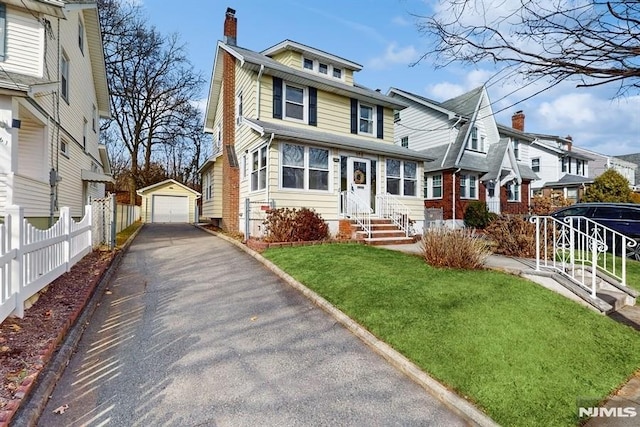 view of front of property featuring a front lawn, a garage, and an outbuilding