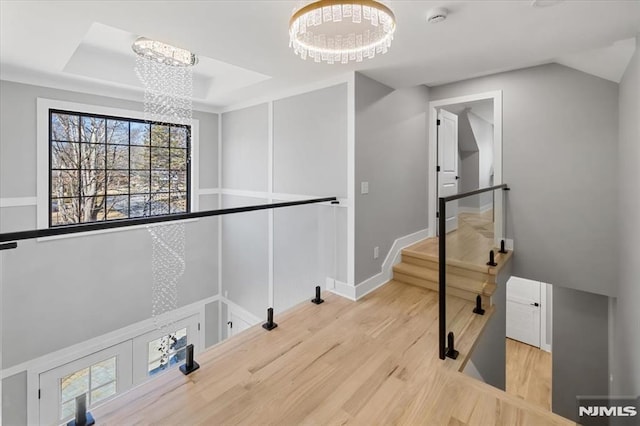 clothes washing area with a notable chandelier, baseboards, and wood finished floors