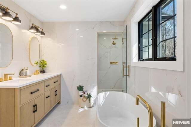 bathroom with a freestanding bath, a sink, tile walls, and a marble finish shower