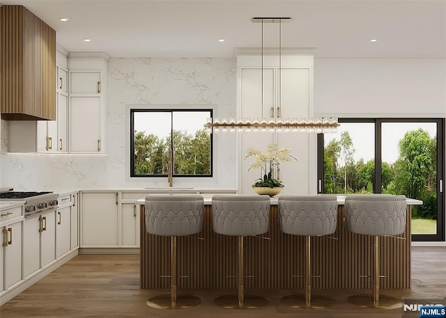 kitchen with white cabinetry, a kitchen breakfast bar, light wood-style floors, light countertops, and decorative backsplash