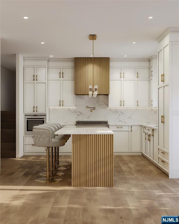 kitchen featuring white cabinets, decorative backsplash, a kitchen island, light countertops, and pendant lighting