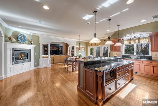 kitchen with light hardwood / wood-style floors, a center island, pendant lighting, and dark stone counters