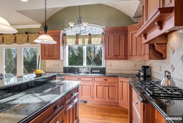 kitchen with stainless steel gas cooktop, decorative light fixtures, an inviting chandelier, and lofted ceiling