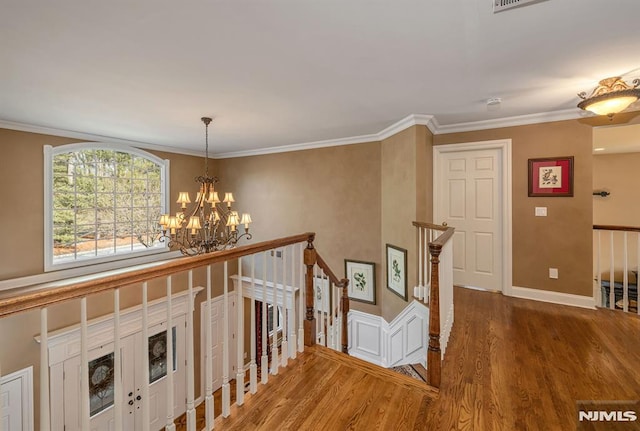 corridor with a notable chandelier, crown molding, and wood-type flooring