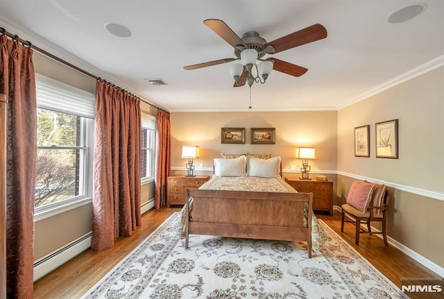 bedroom with a baseboard heating unit, ceiling fan, light hardwood / wood-style floors, and ornamental molding